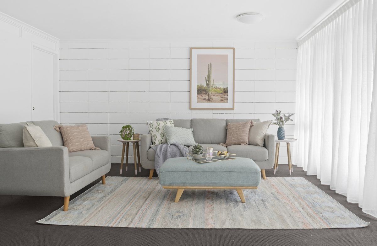 A living room with a couch , ottoman , and rug.