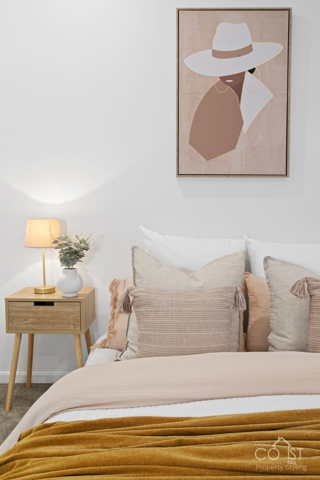 A bedroom with a bed , nightstand , lamp and painting on the wall.