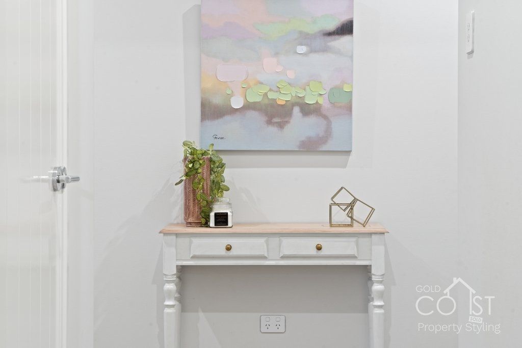 A white table with a painting on the wall above it.