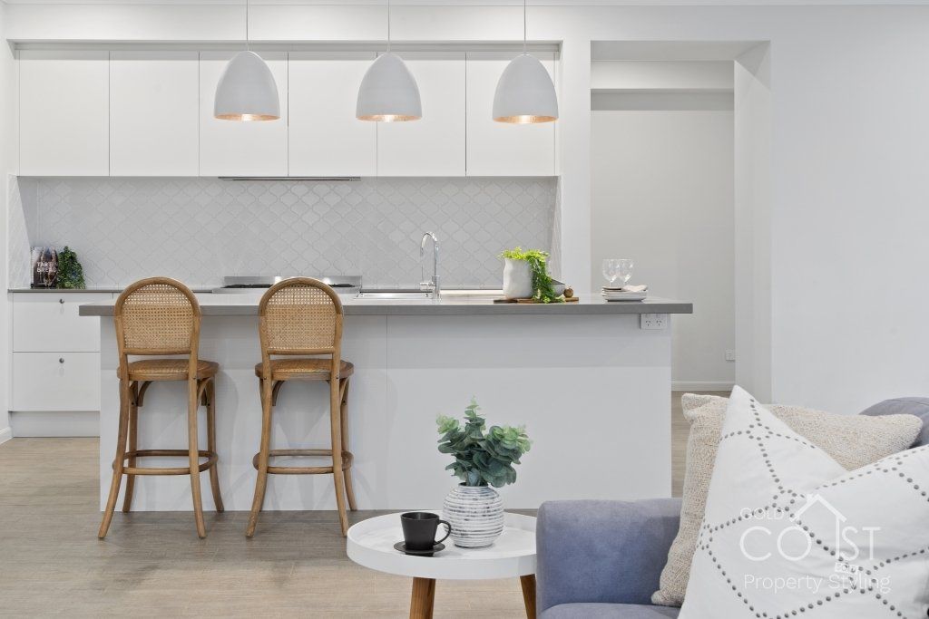 A living room with a couch , table , chairs and a kitchen.