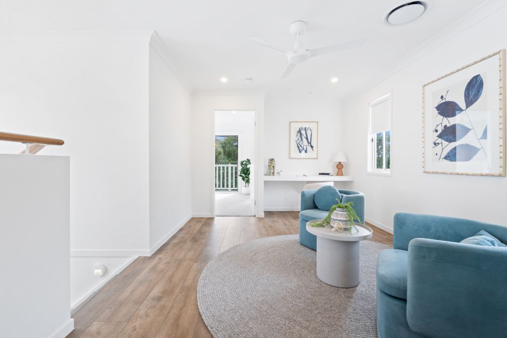 Bright modern living room with white walls, blue chairs, round rug, and artwork on the wall