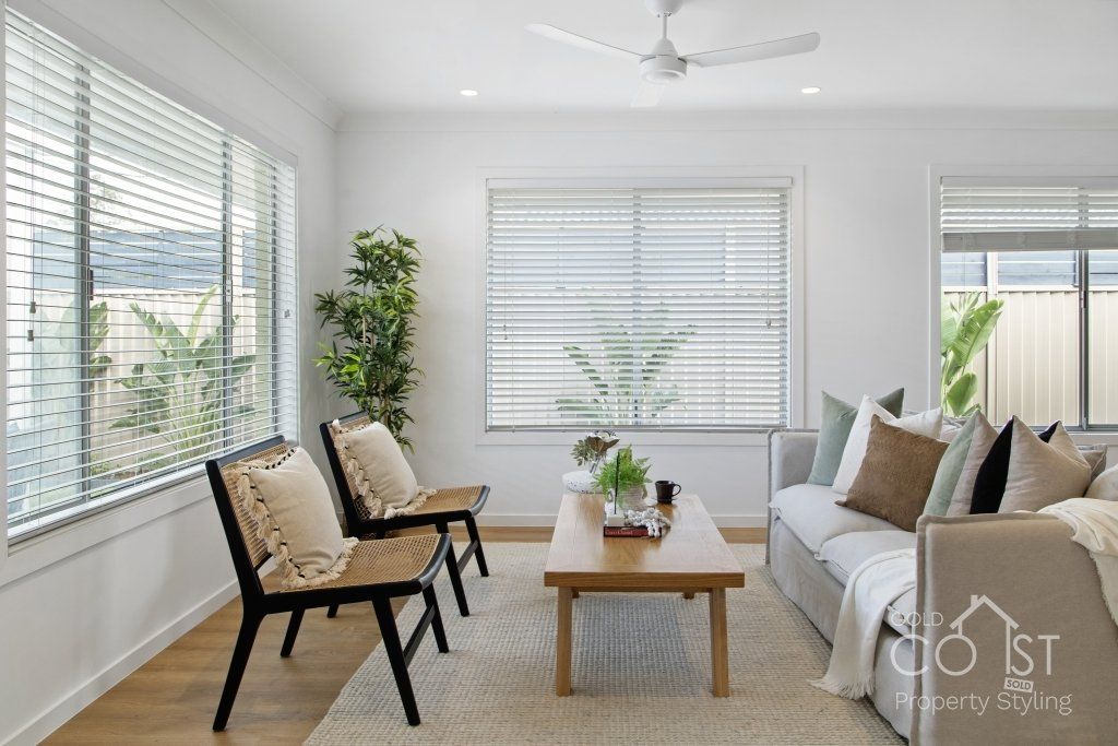 A living room with a couch , chairs , coffee table and ceiling fan.