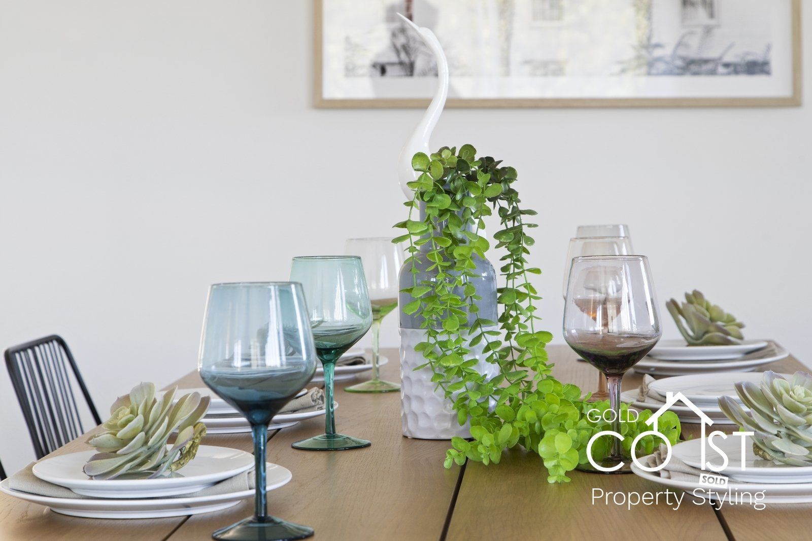 A table with plates , wine glasses , and a plant on it.