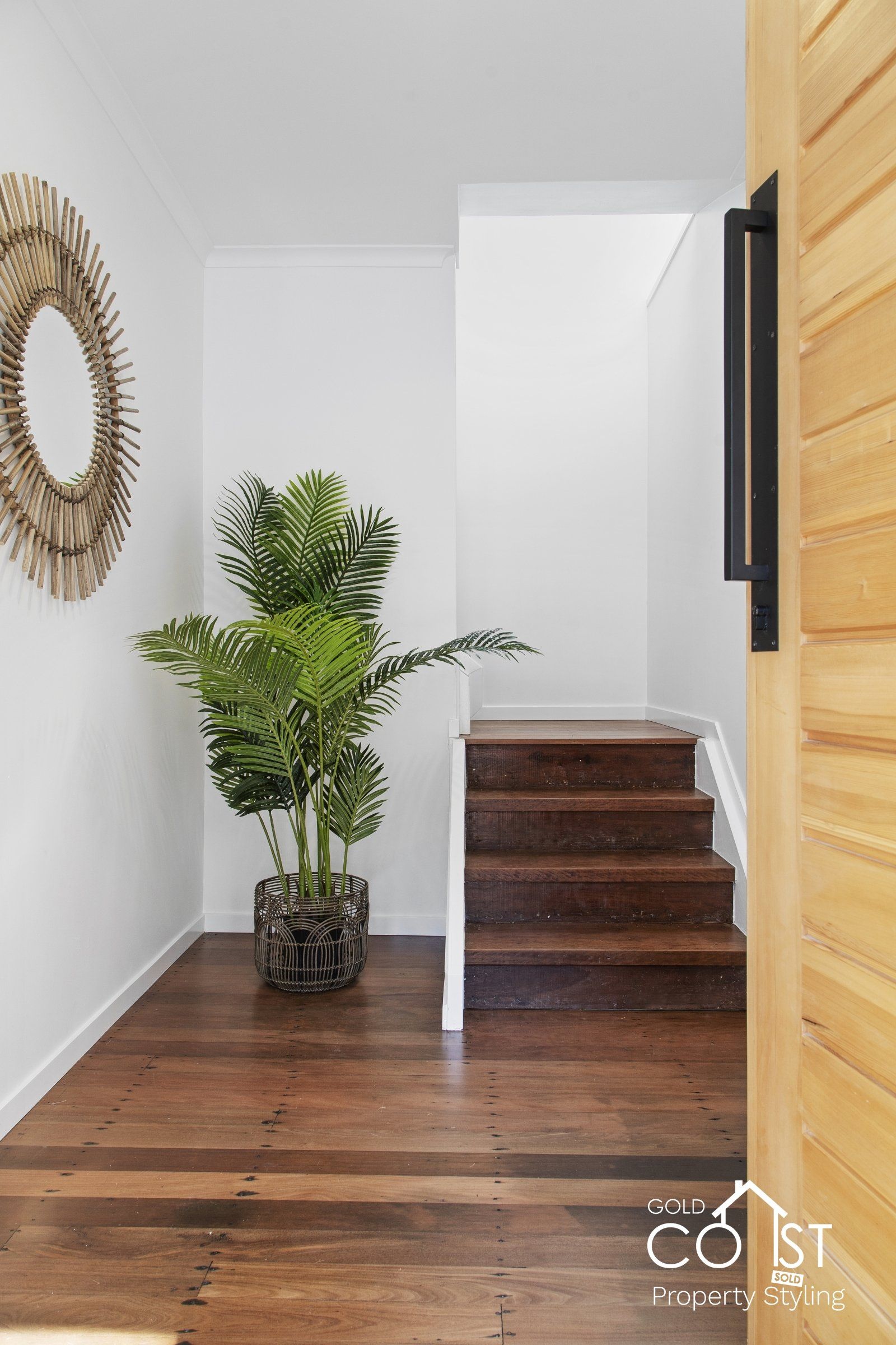 A potted plant is sitting in a hallway next to stairs.