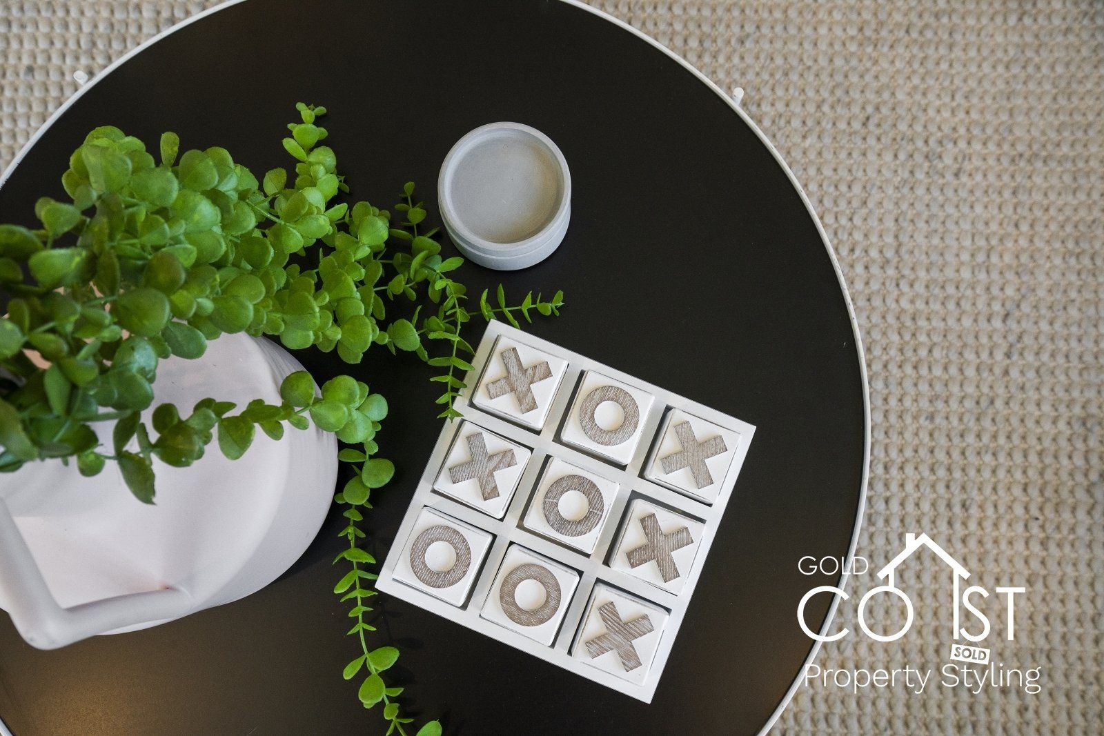 A black table with a plant and a tic tac toe game on it.