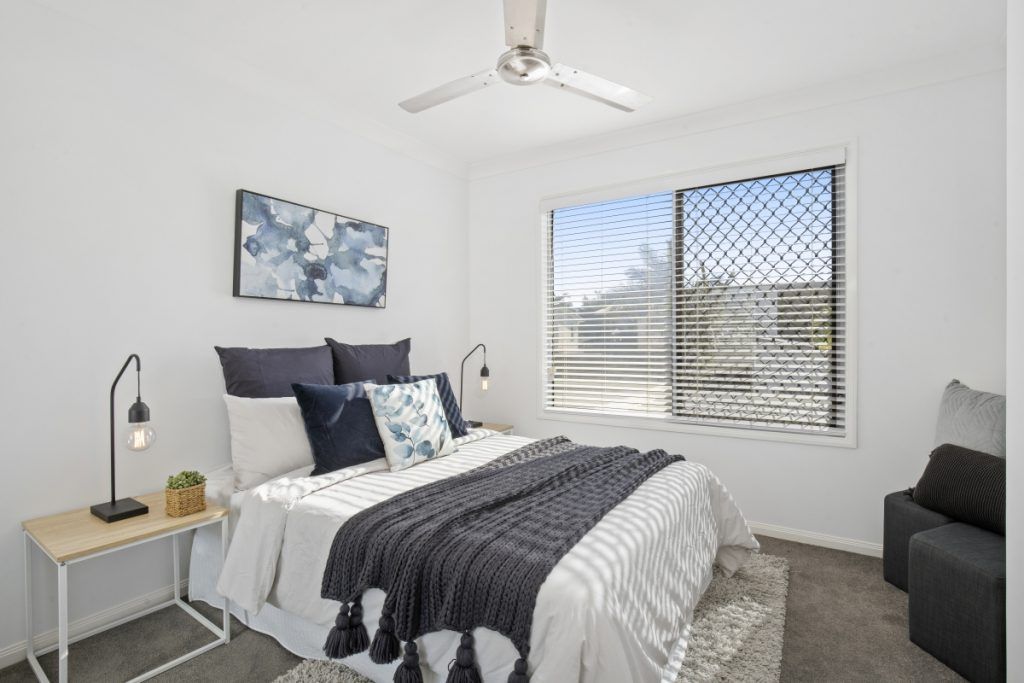 A bedroom with a bed and a ceiling fan.