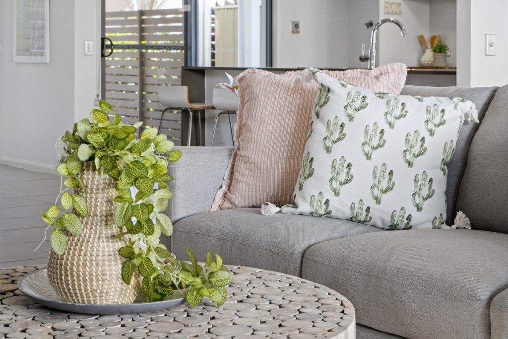 A living room with a couch , coffee table , and pillows.