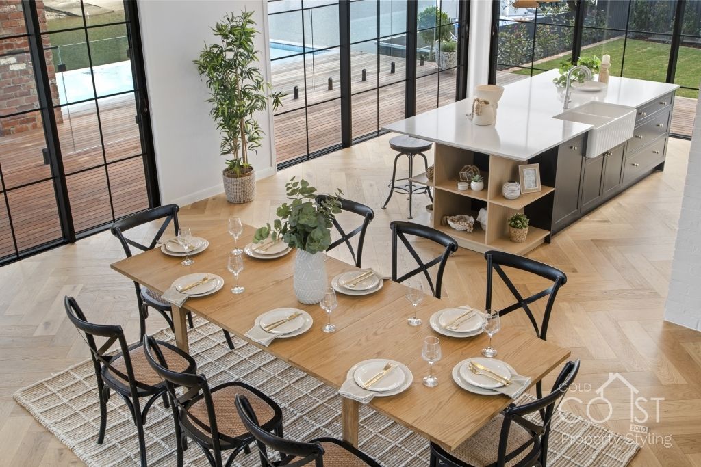 A dining room with a table and chairs and plates on it.