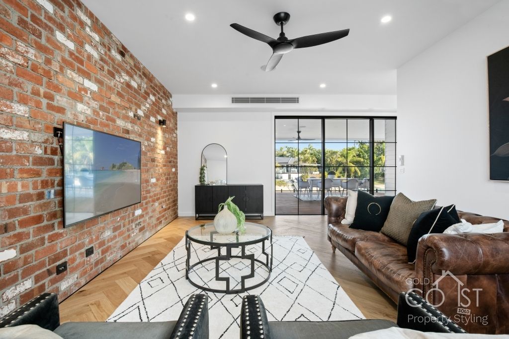 A living room with a couch , table , television and ceiling fan.