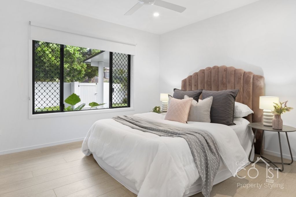 A bedroom with a bed and a window with a ceiling fan.