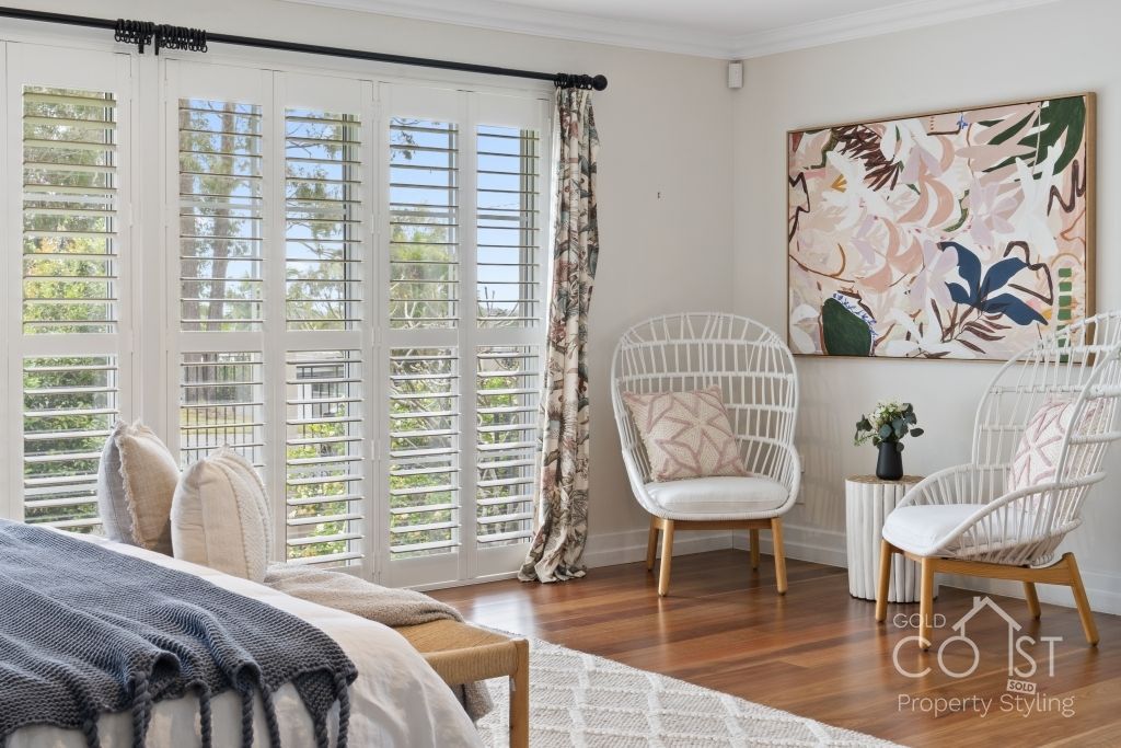 A bedroom with a large bed , chairs , lamps and a rug.
