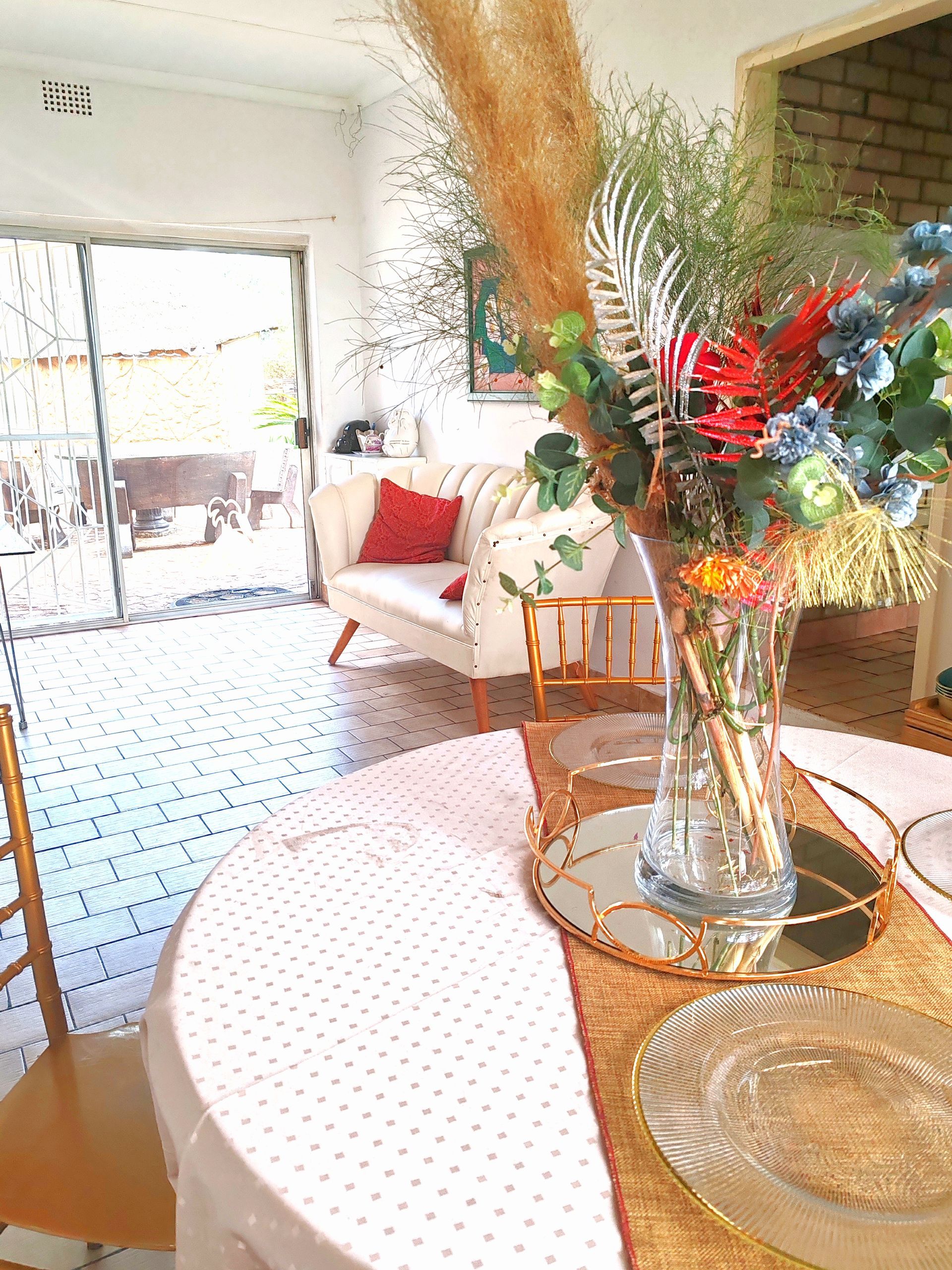 Bright living room with a floral bouquet on a round table and a sofa by a sunlit window