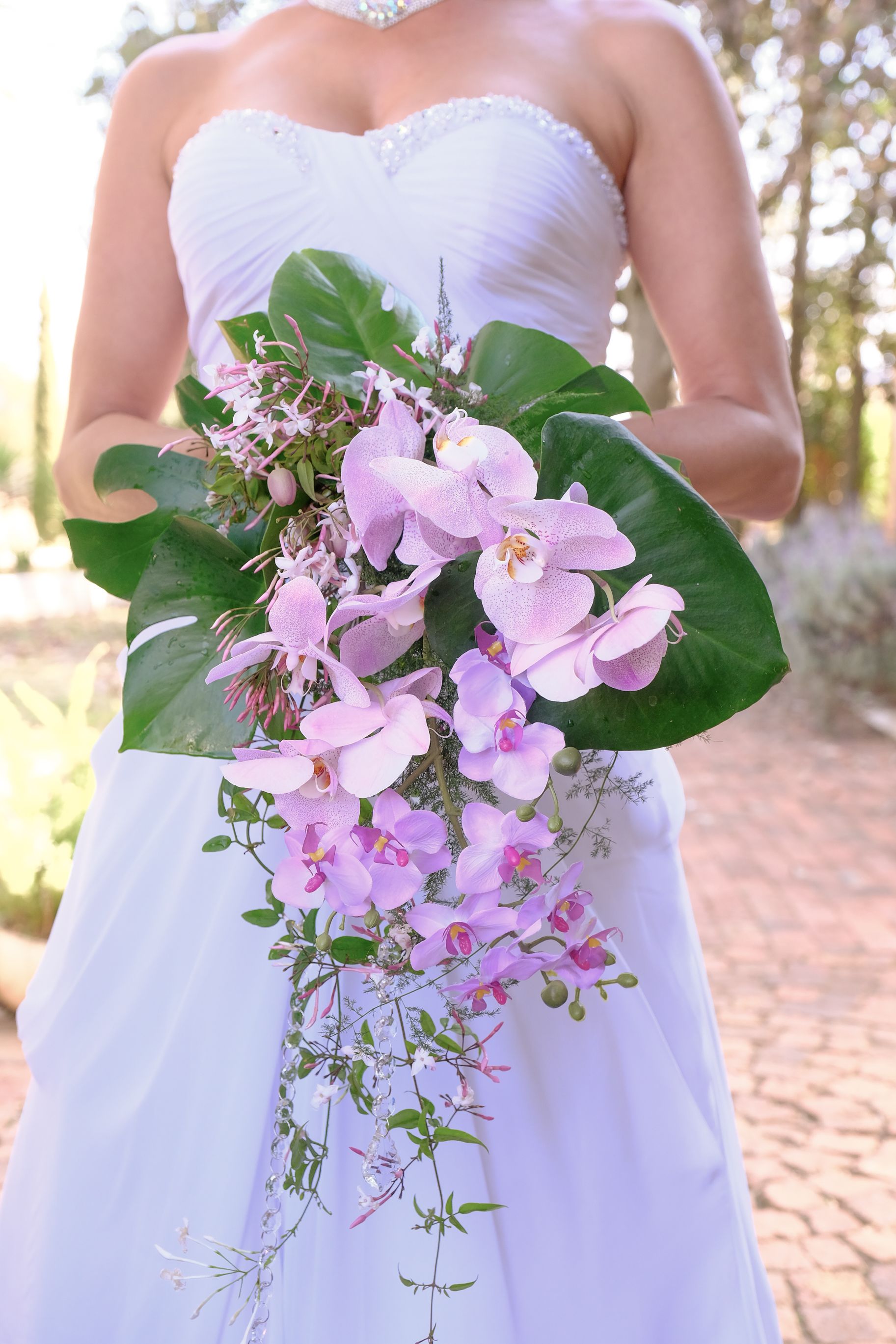 A bride in a white dress is holding a bouquet of pink flowers.