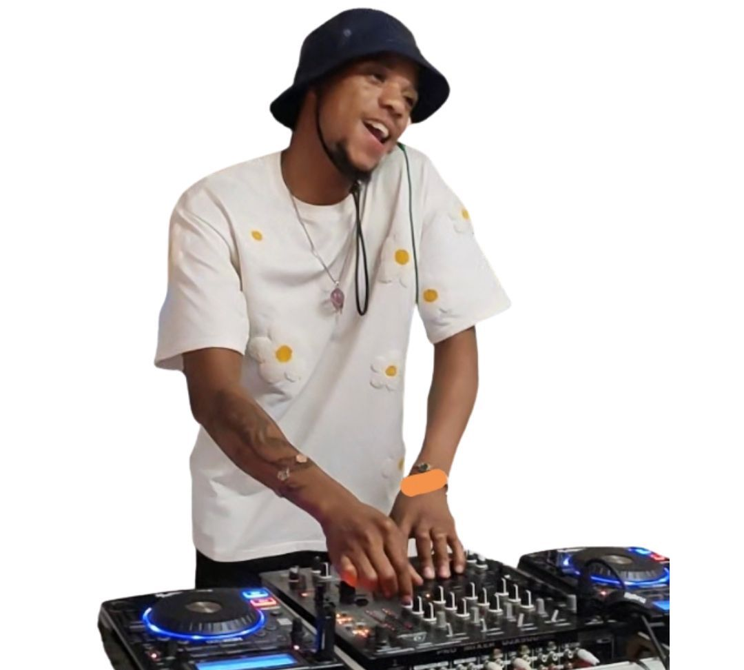 DJ in a black hat mixing music on a controller, wearing a white shirt and orange wristband