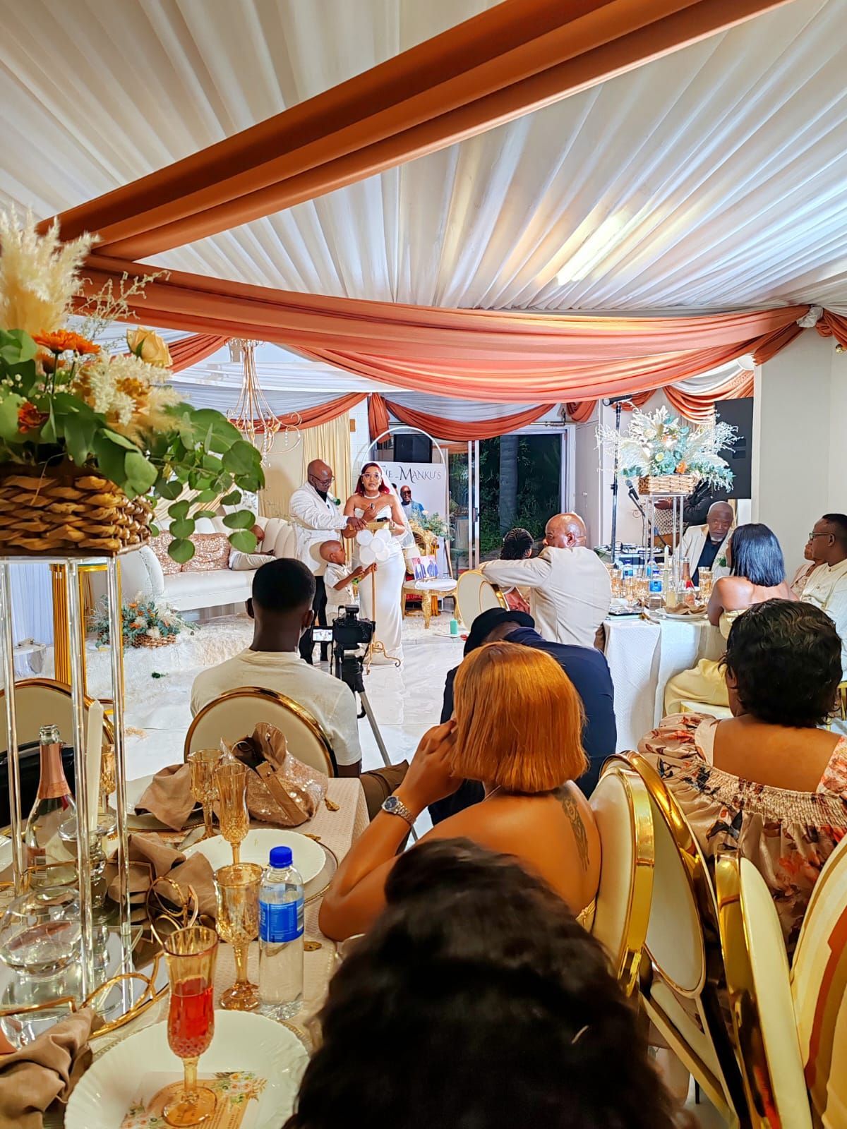 Guests seated under peach drapes at a formal indoor banquet reception