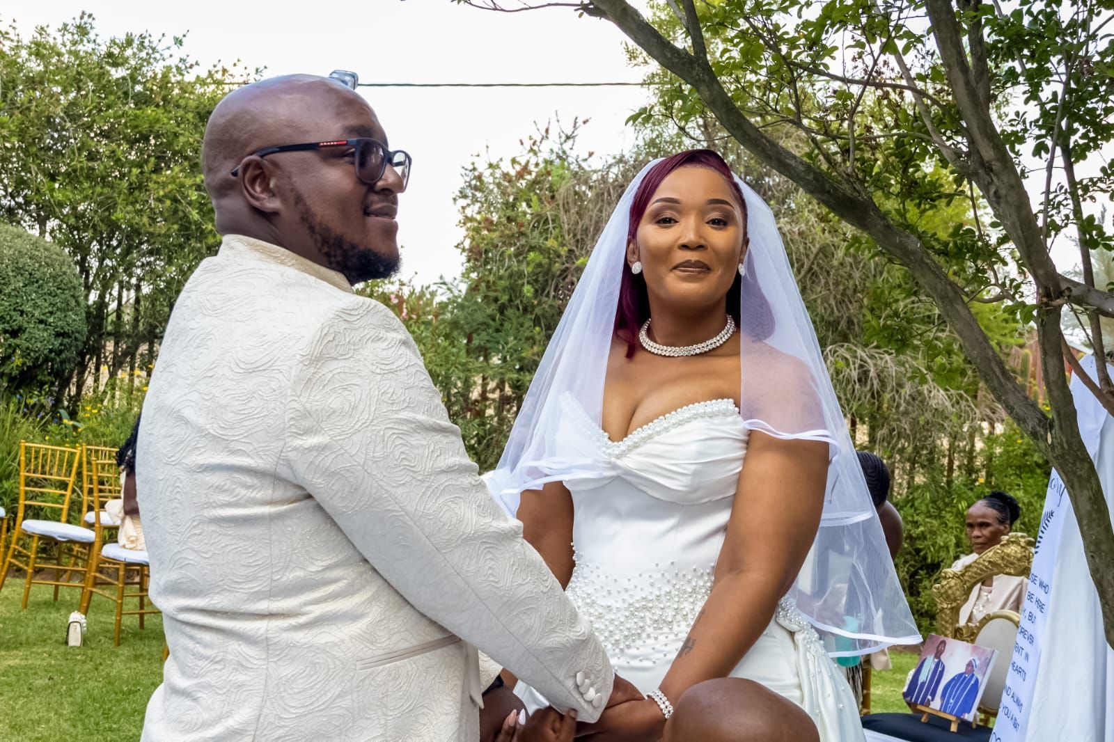 Bride and groom holding hands outdoors, smiling during a wedding ceremony.