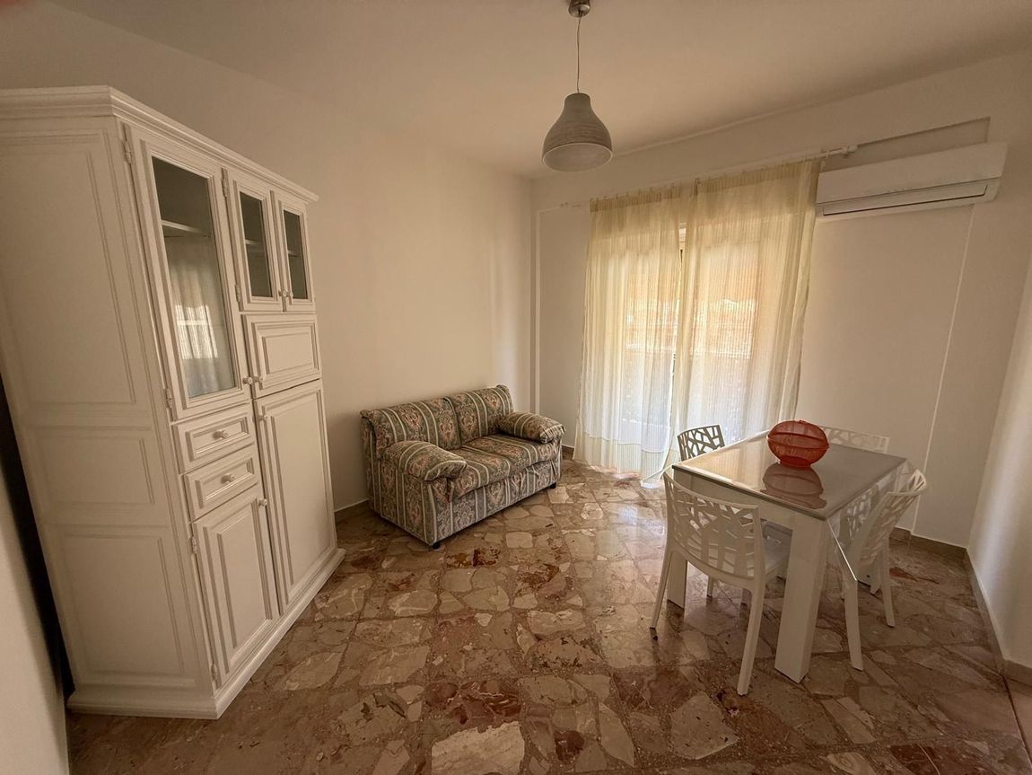 Un bagno moderno con doccia con box in vetro, pareti rivestite con piastrelle scure, un portasciugamani a scala bianco e una lampada a sospensione dal design unico.
