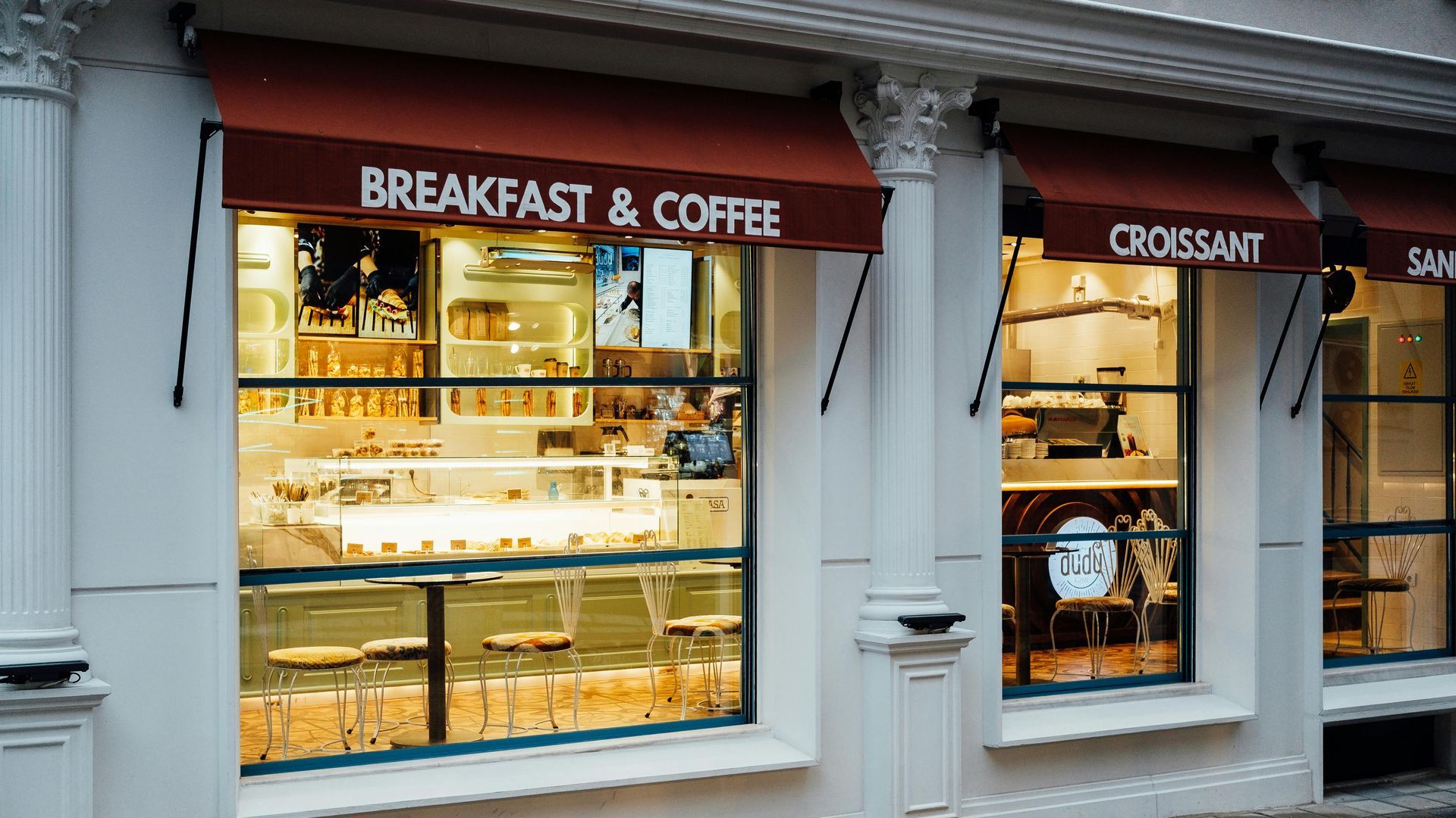 Bakery storefront with lit display windows, “Breakfast & Coffee” and “Croissant” signs