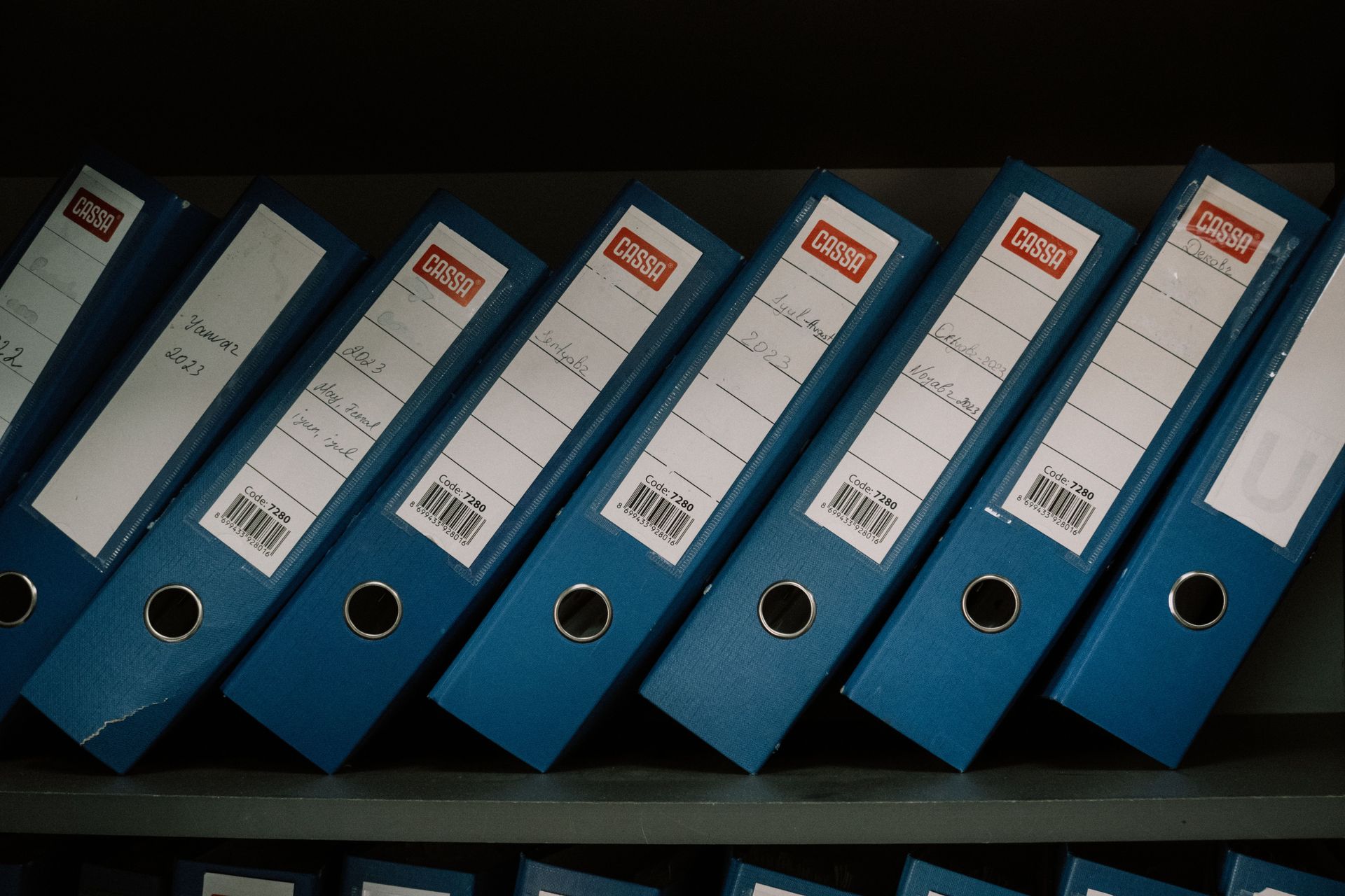 Row of labelled binders holding business records on a shelf