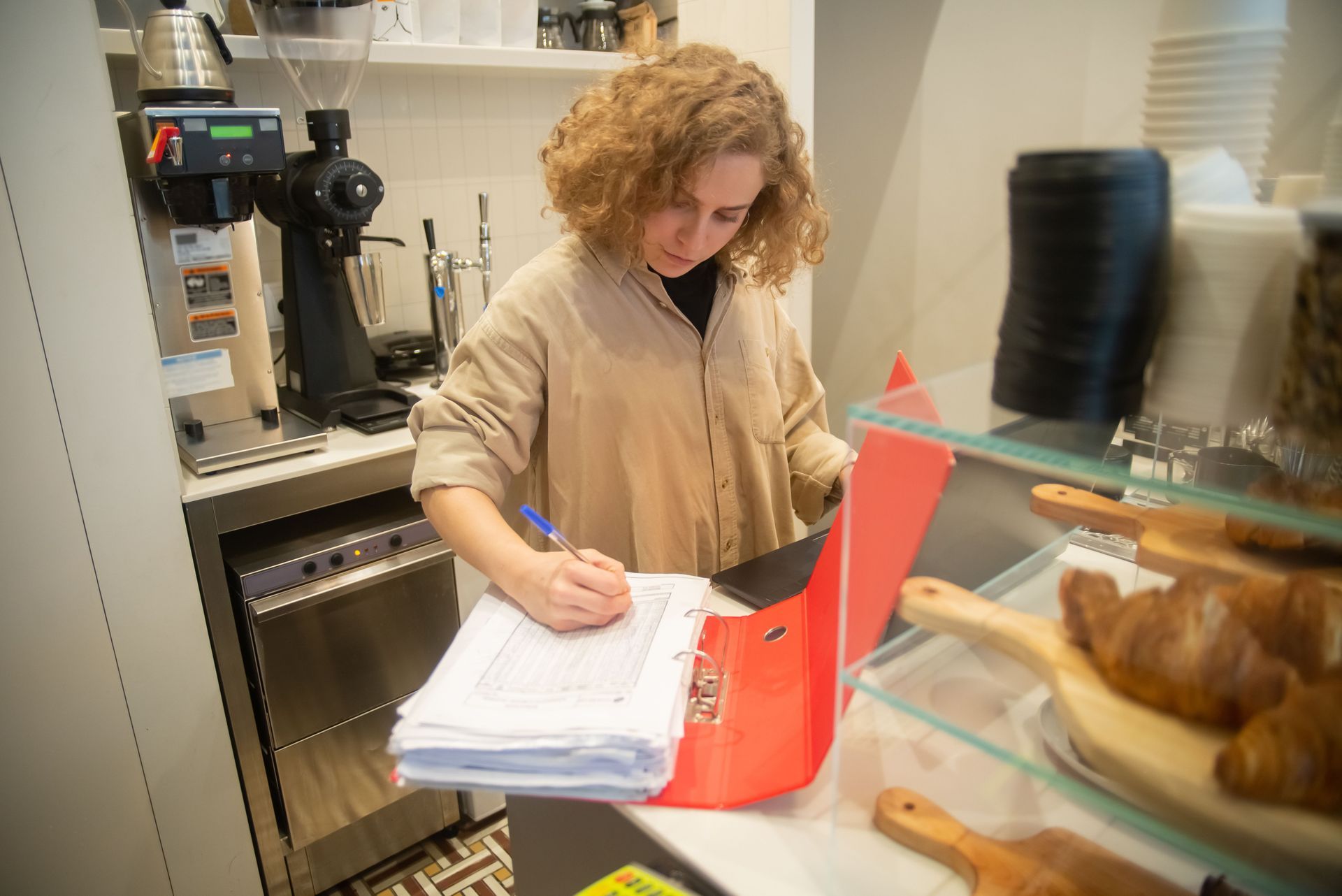 Cafe owner completing payroll paperwork behind the counter of her small business