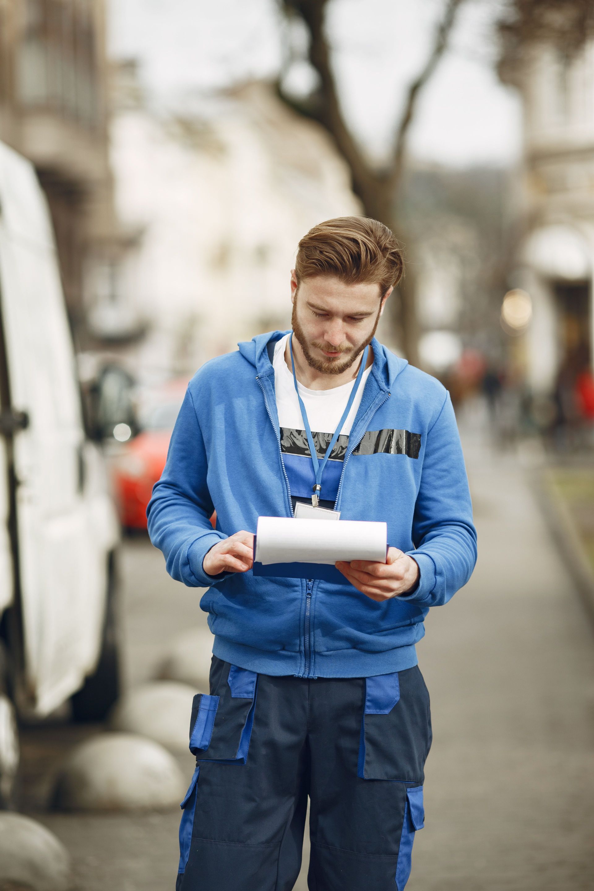 Tradesman checking contractor payment paperwork beside his work van