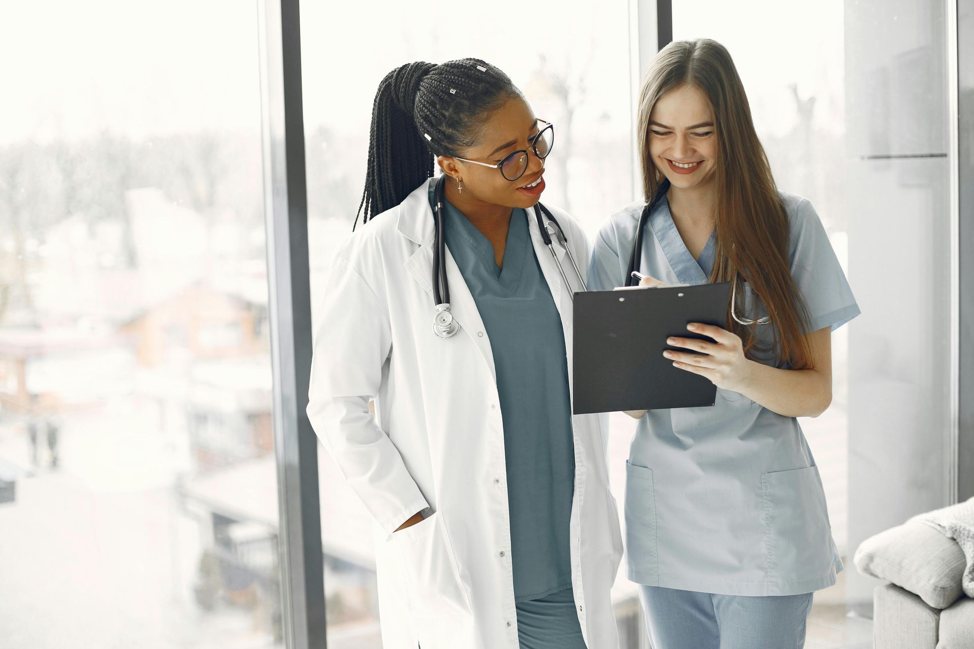 Two medical professionals reviewing a tablet in a bright hospital corridor
