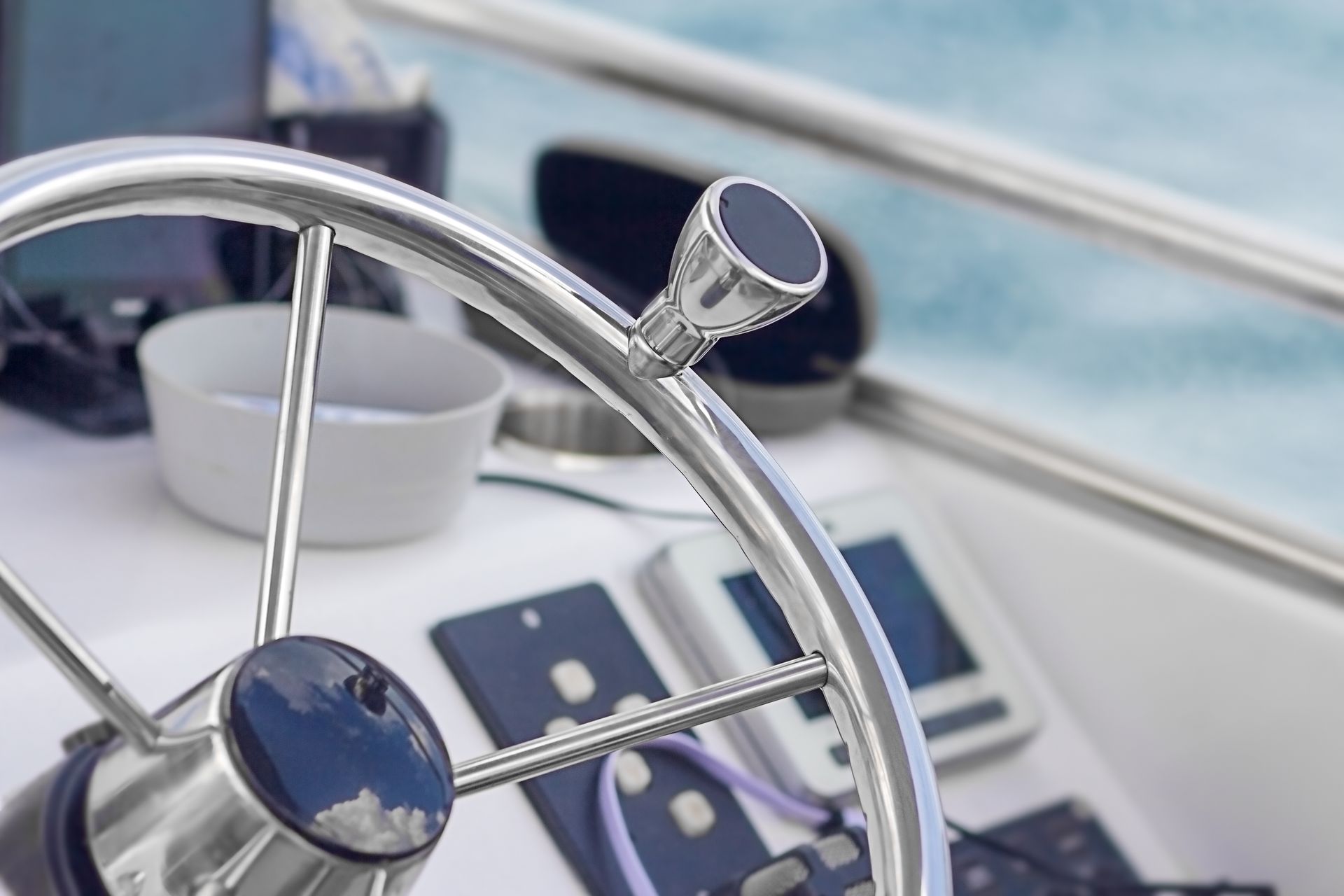 Boat steering wheel, chrome and black, with ocean background.