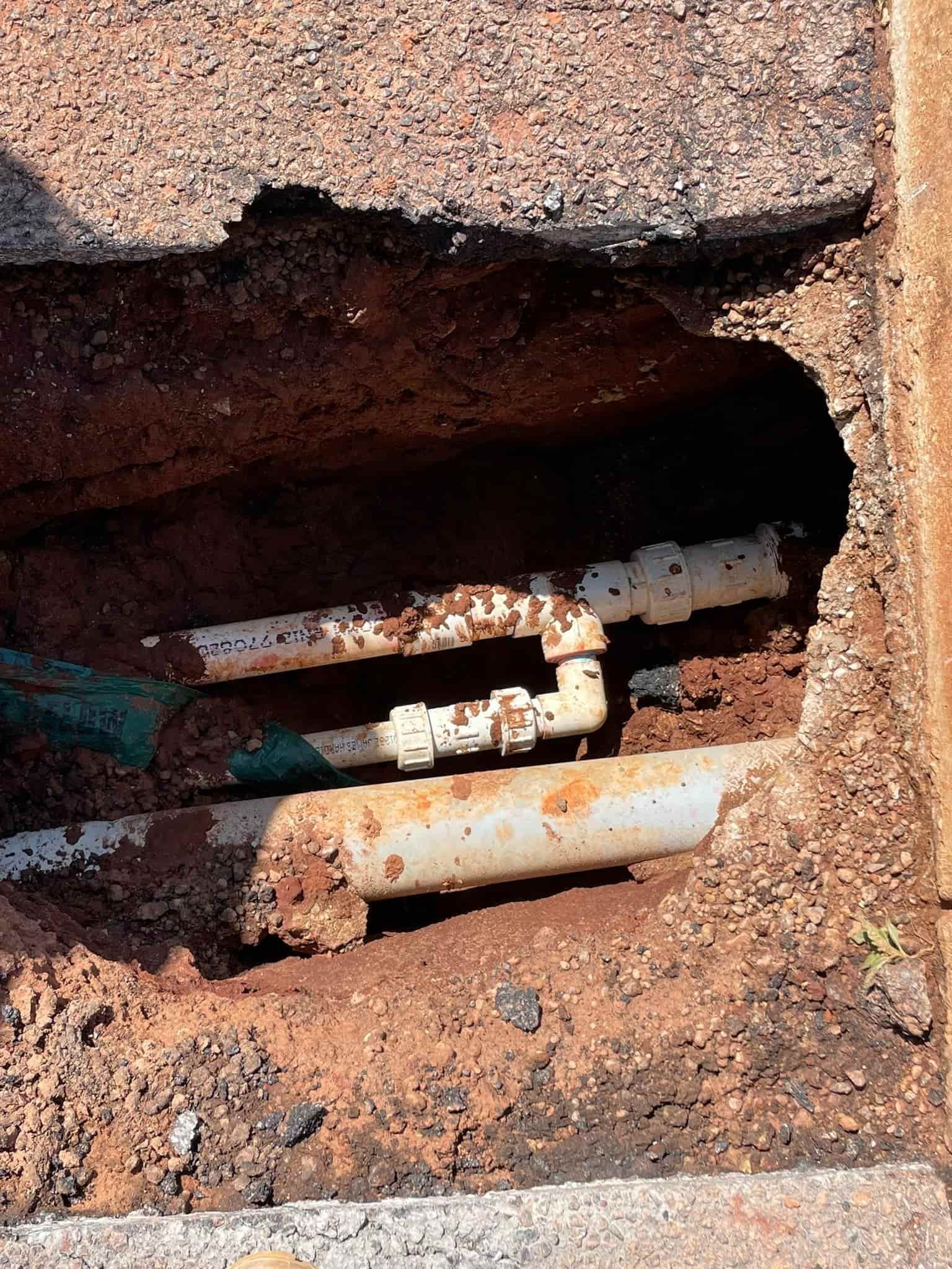 Pipes Exposed in a Hole in Asphalt and Dirt — Tap & Drain Doctor NT in Winnellie, NT