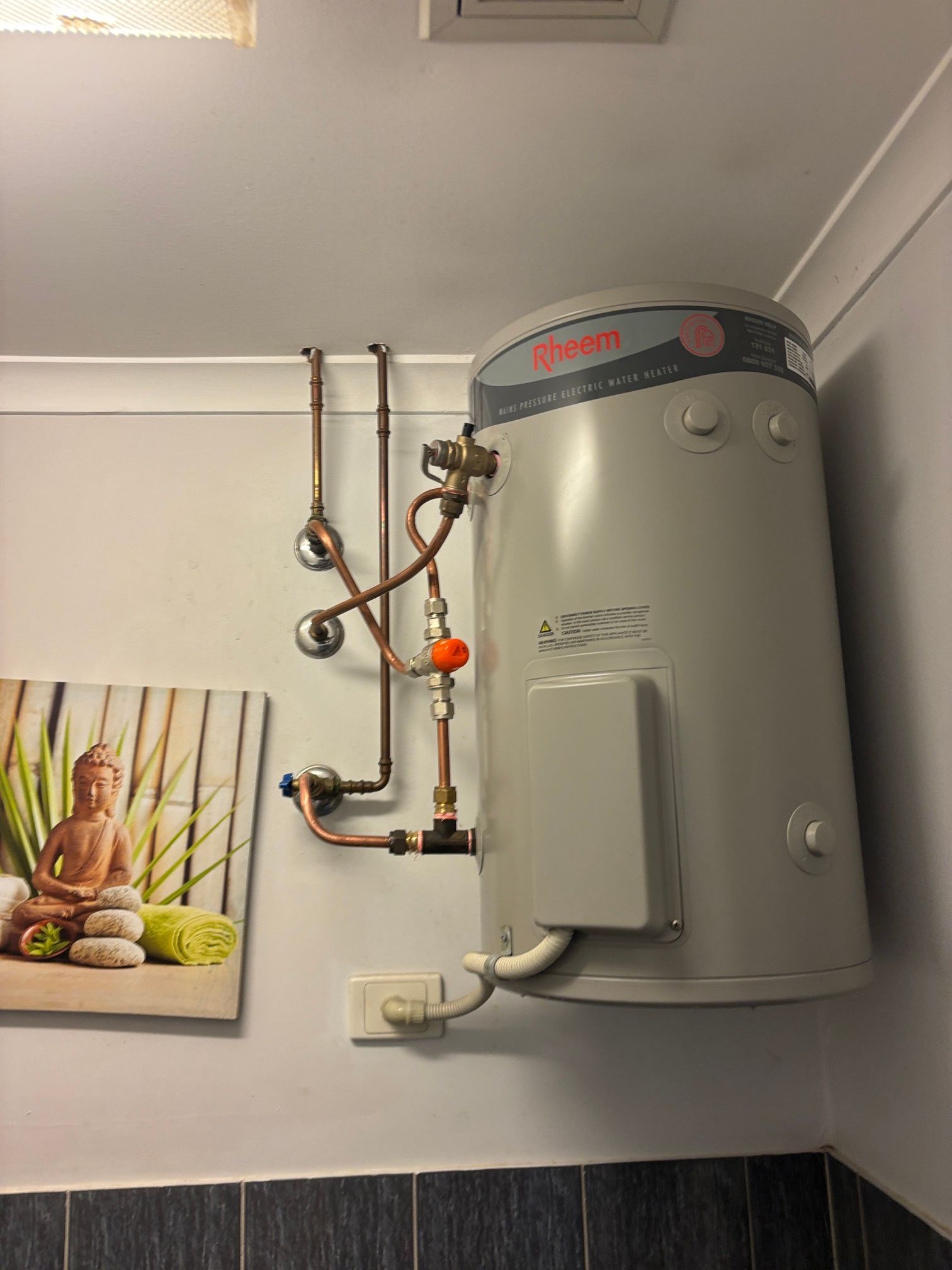 Wall-mounted water heater with exposed copper pipes and wall art in a bathroom-like room — Tap & Drain Doctor NT in Winnellie, NT