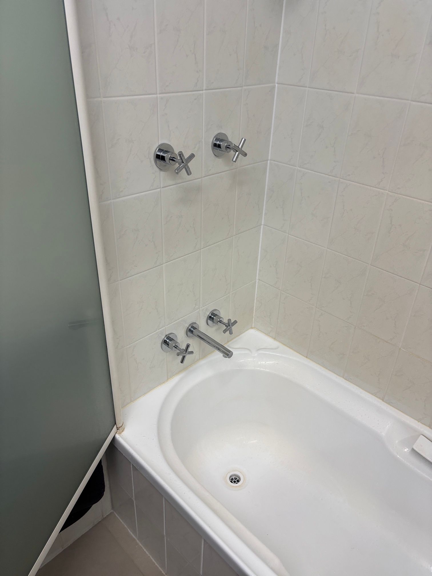 Bathtub corner with tiled shower wall and chrome faucet fixtures — Tap & Drain Doctor NT in Winnellie, NT