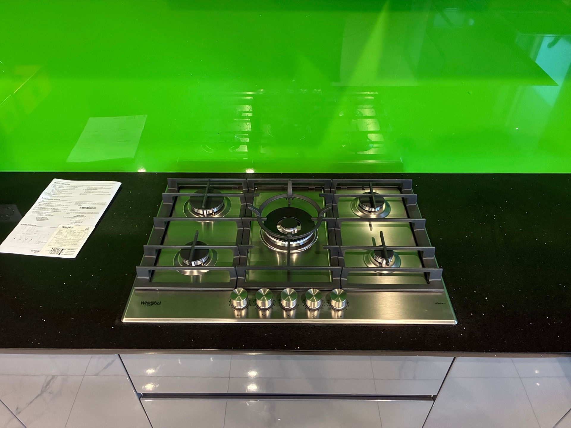 Modern kitchen countertop with stainless steel gas cooktop and bright green backsplash — Tap & Drain Doctor NT in Winnellie, NT