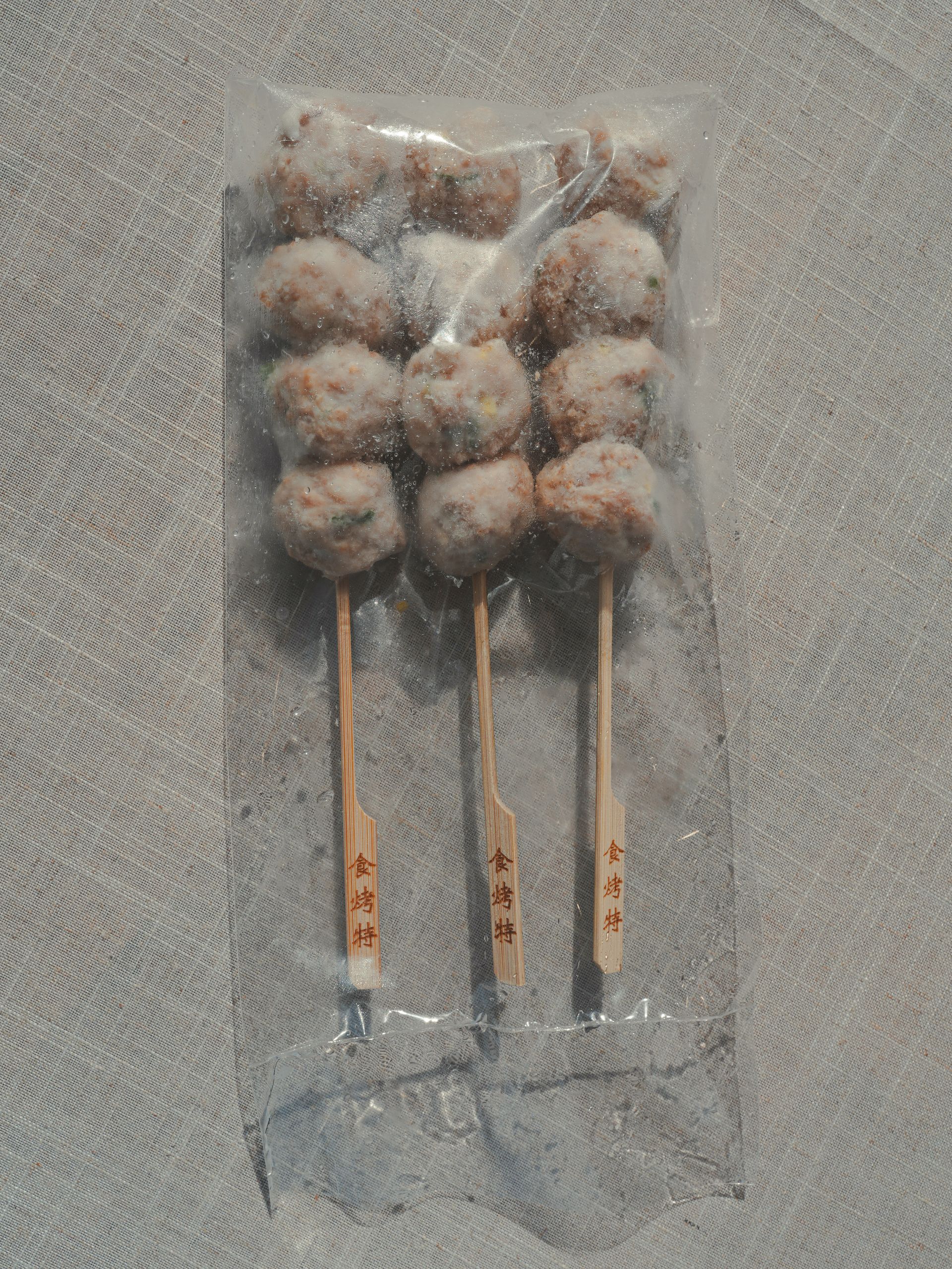 肉丸串在烤肉籤上，配上歐芹和櫻桃番茄，放在木板上。