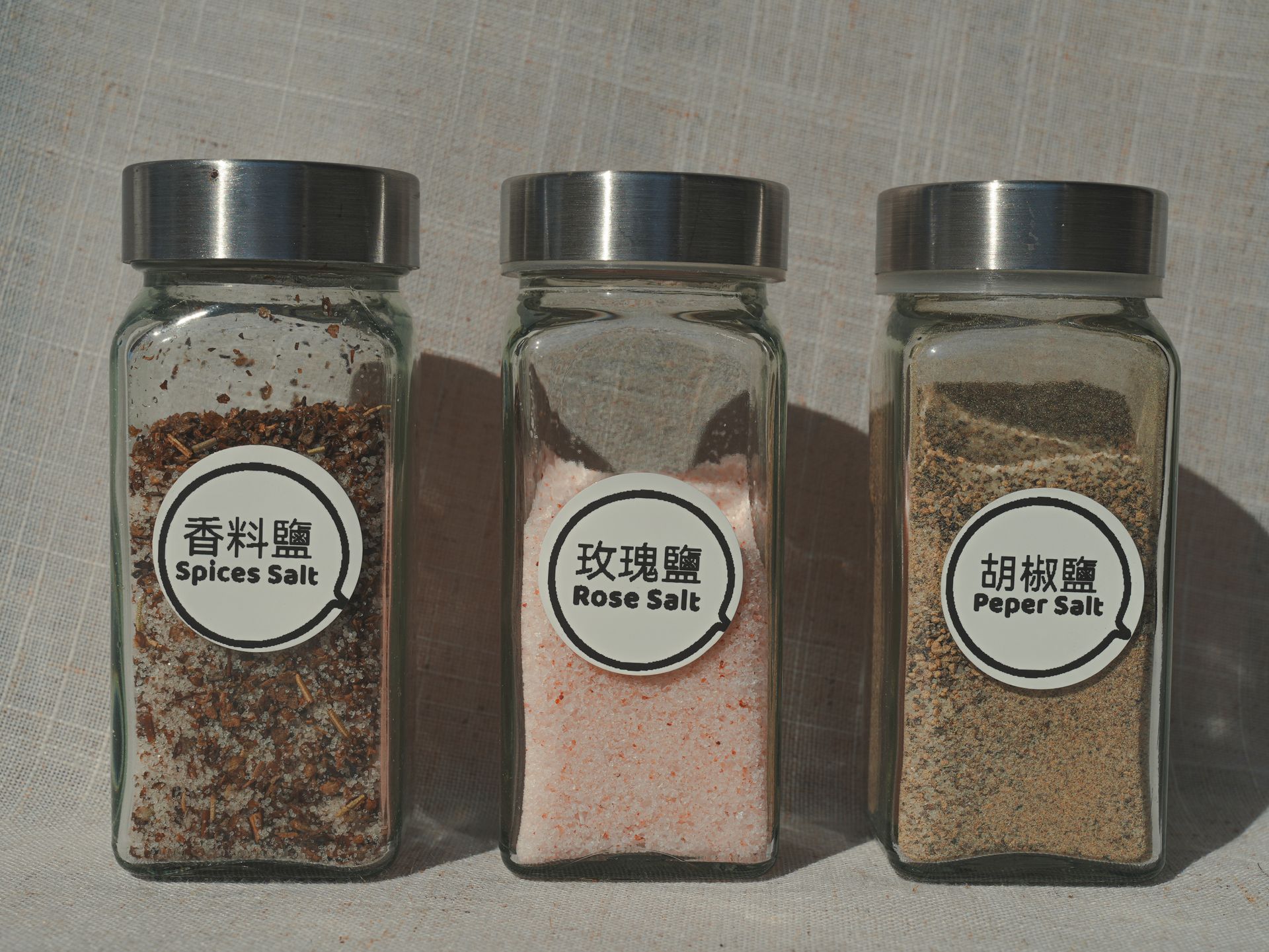 白色桌布上放著一個裝有胡椒鹽的玻璃罐，旁邊還有一個裝有胡椒鹽的小黑碟。