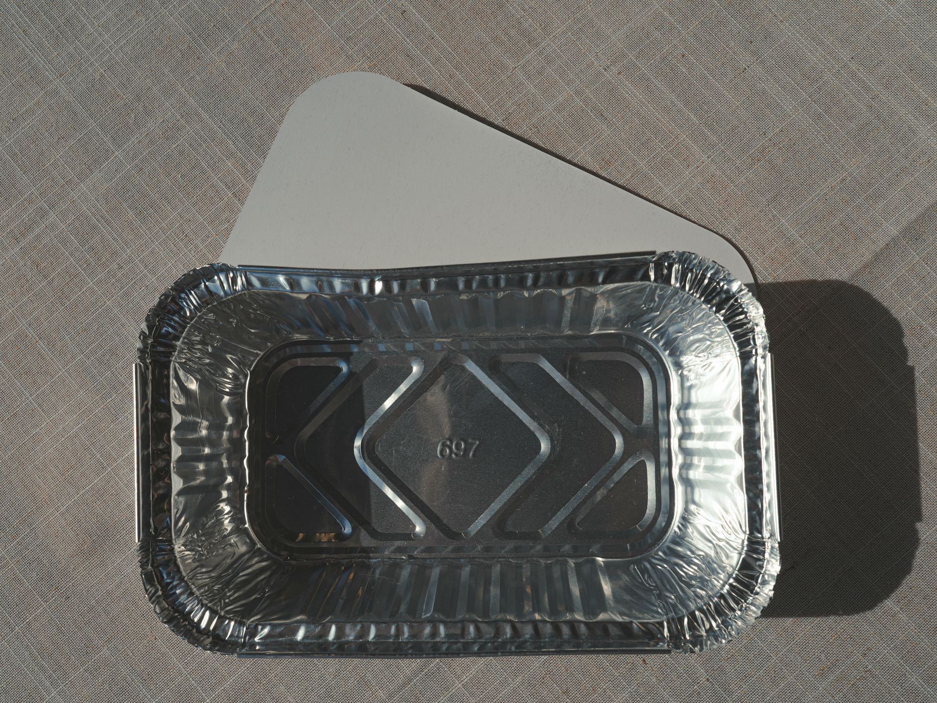 帶蓋鋁箔食品容器，放置在紋理表面上。