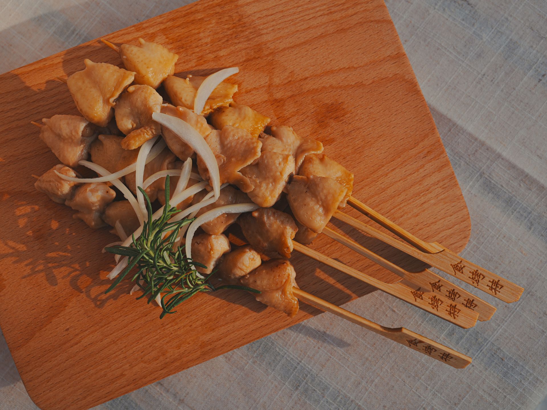 雞肉串配洋蔥和迷迭香，放在木板上。