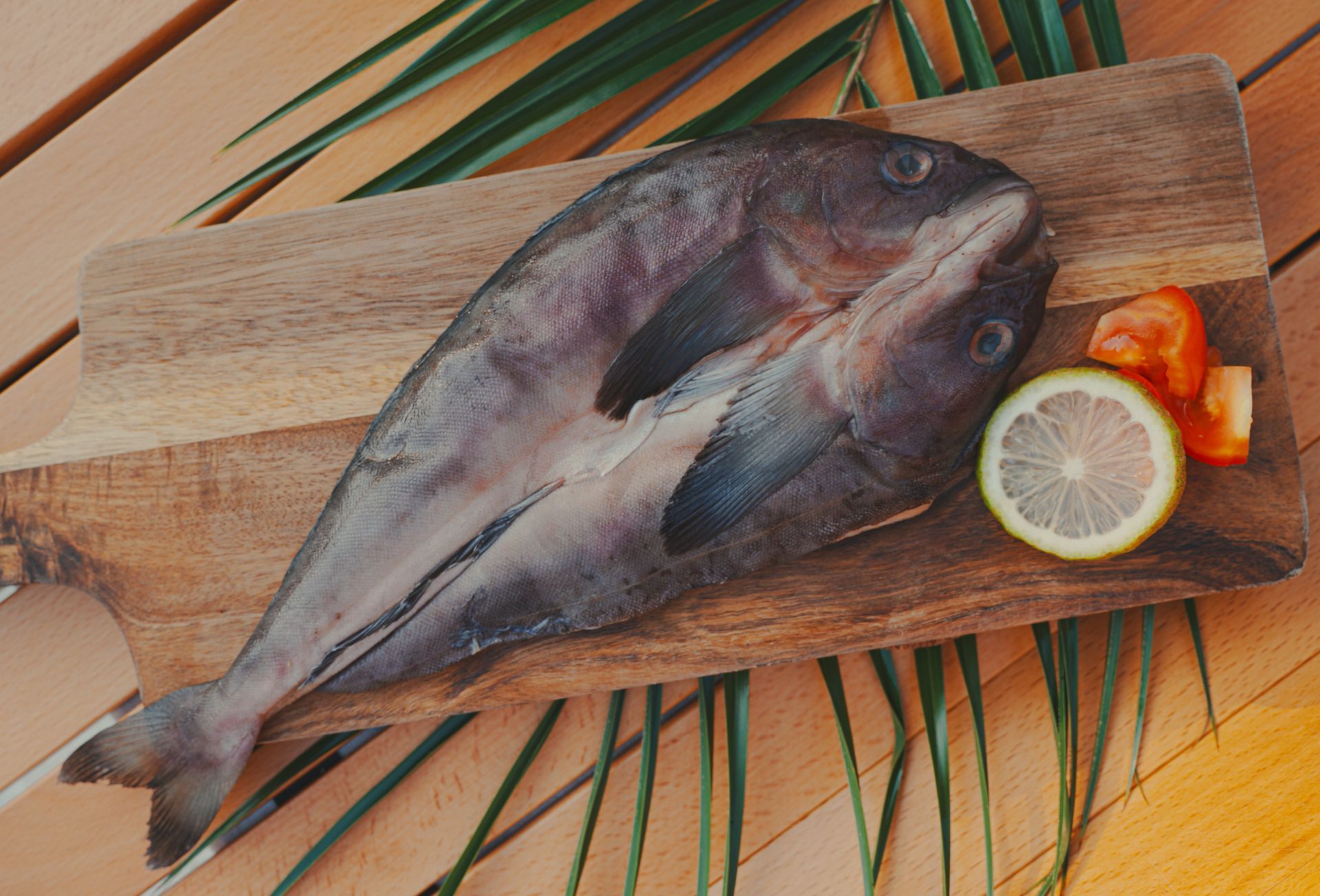 木質砧板上放著生魚片、檸檬片和番茄片。