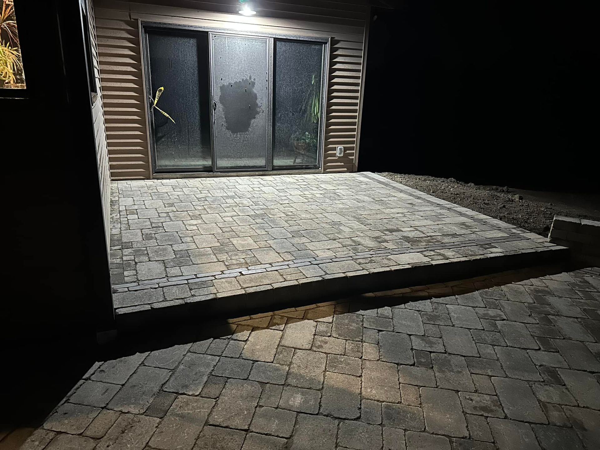 A patio with a sliding glass door is lit up at night.
