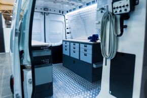 Inside of a utility van with tool storage, drawers, work surface, and hanging equipment.