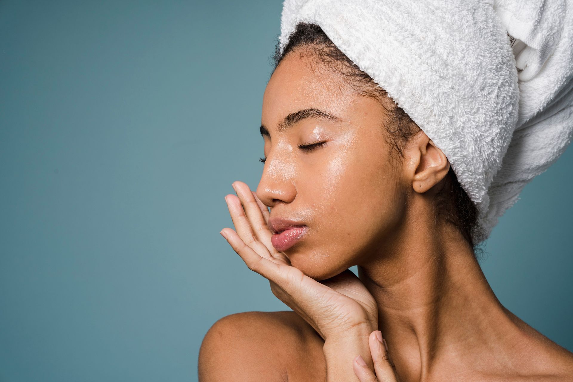 Woman with hair wrapped in a towel and one hand on her face