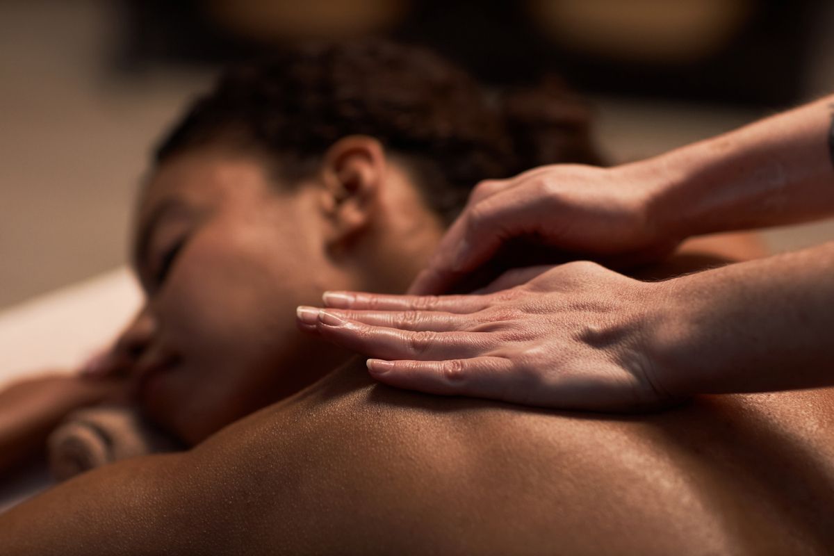Hands giving a back massage to a person lying face down in a spa setting