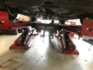Car on a red Hunter lift in a garage. Underside of the car is visible.