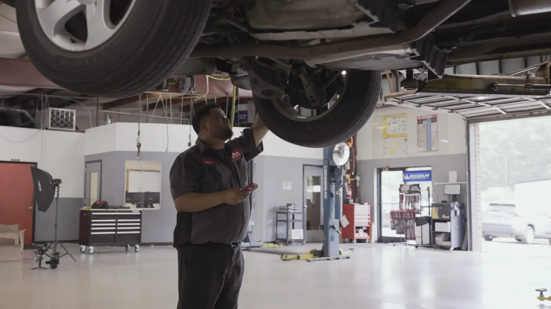 Mechanic inspecting car undercarriage in a garage.