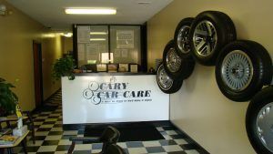 Car care shop interior with tires on the wall, a reception desk, and checkered floor.
