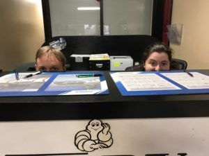 Two people peering over a counter, looking at paperwork. Michelin Man logo on the counter.