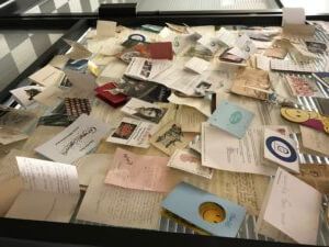 Pile of scattered cards, notes, and ephemera on a reflective surface, possibly a display.