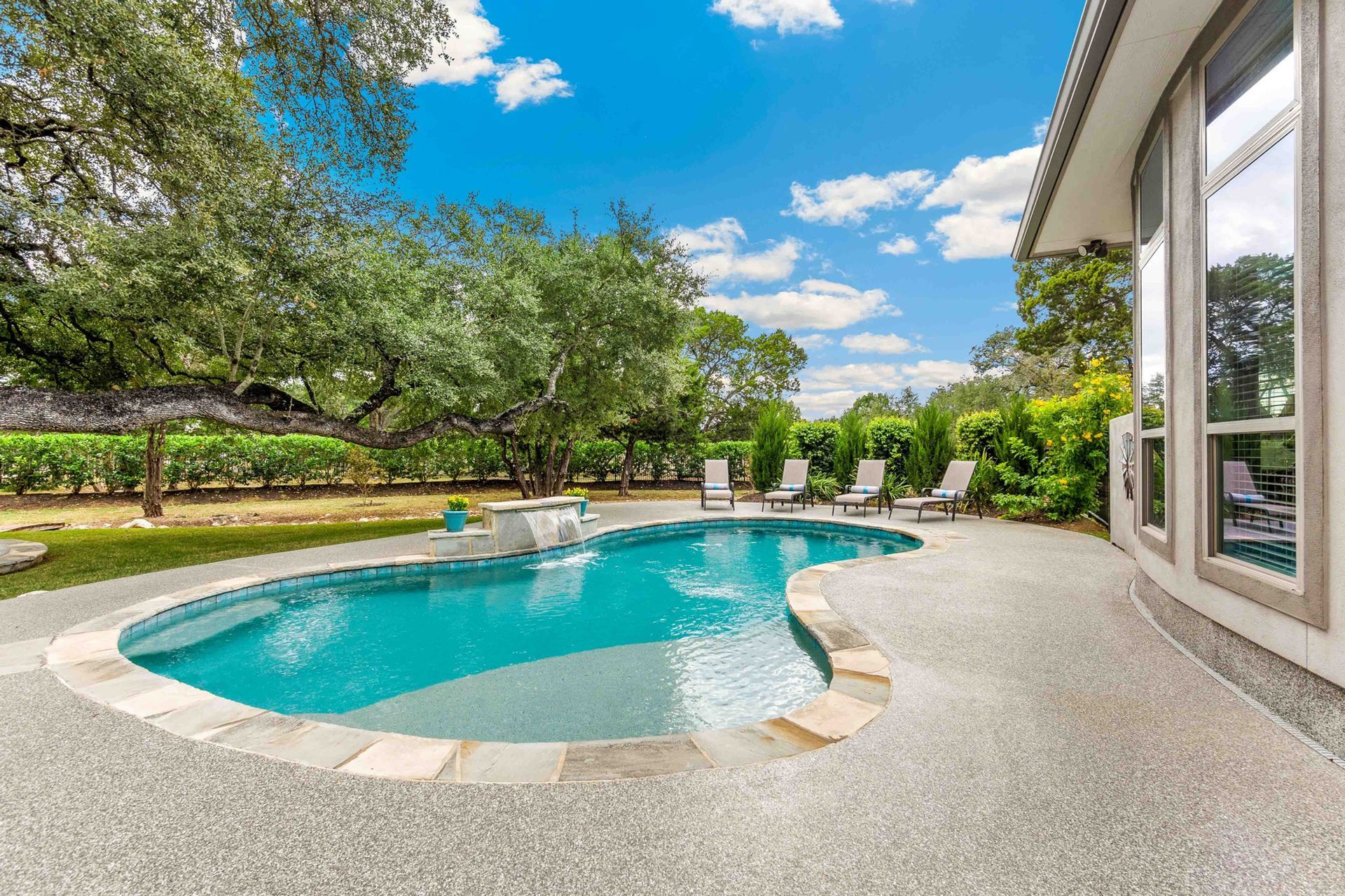 There is a large swimming pool in the backyard of a house.