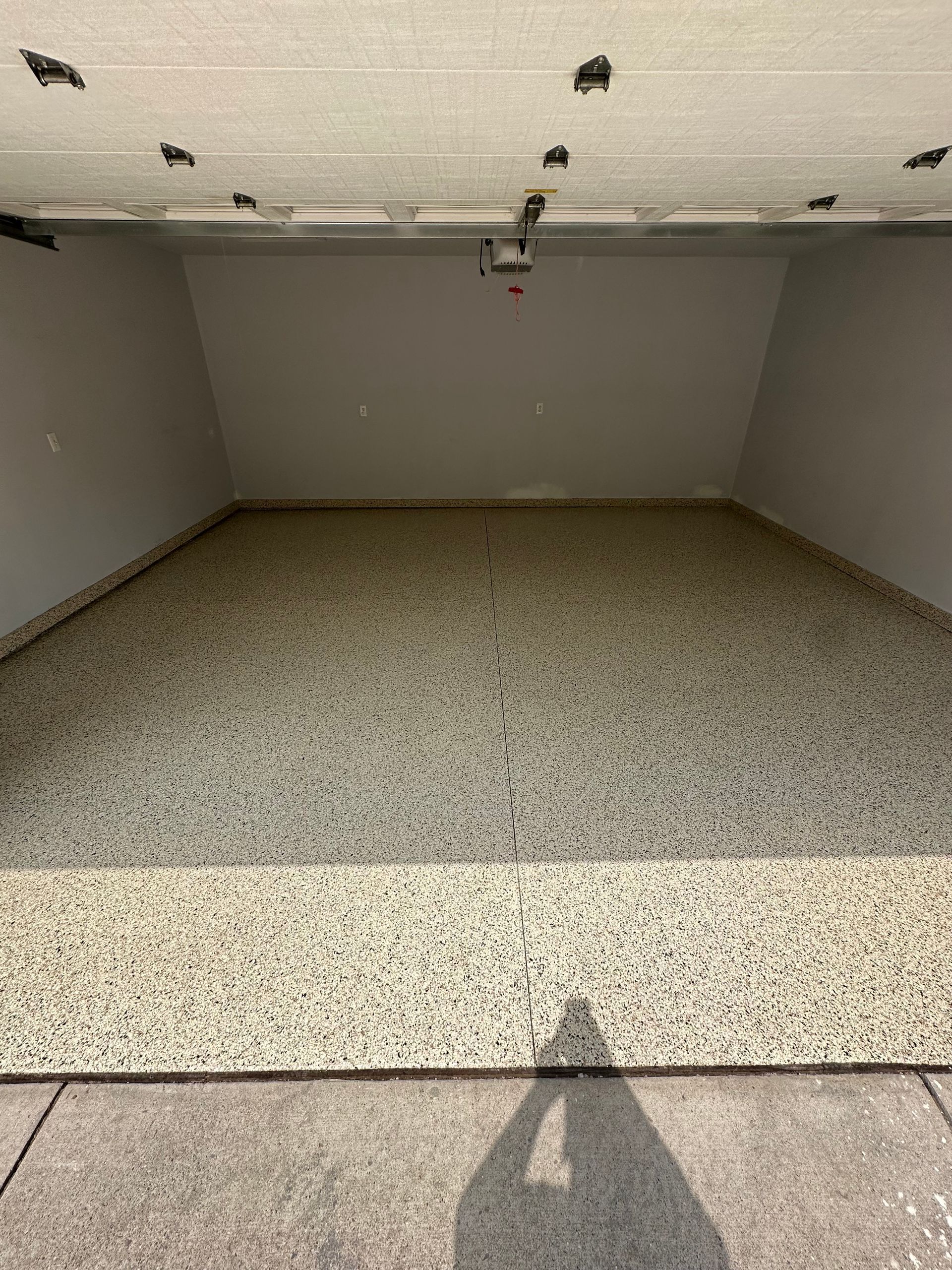 Empty carpeted room with gray walls and a speckled ceiling, viewed from the doorway.