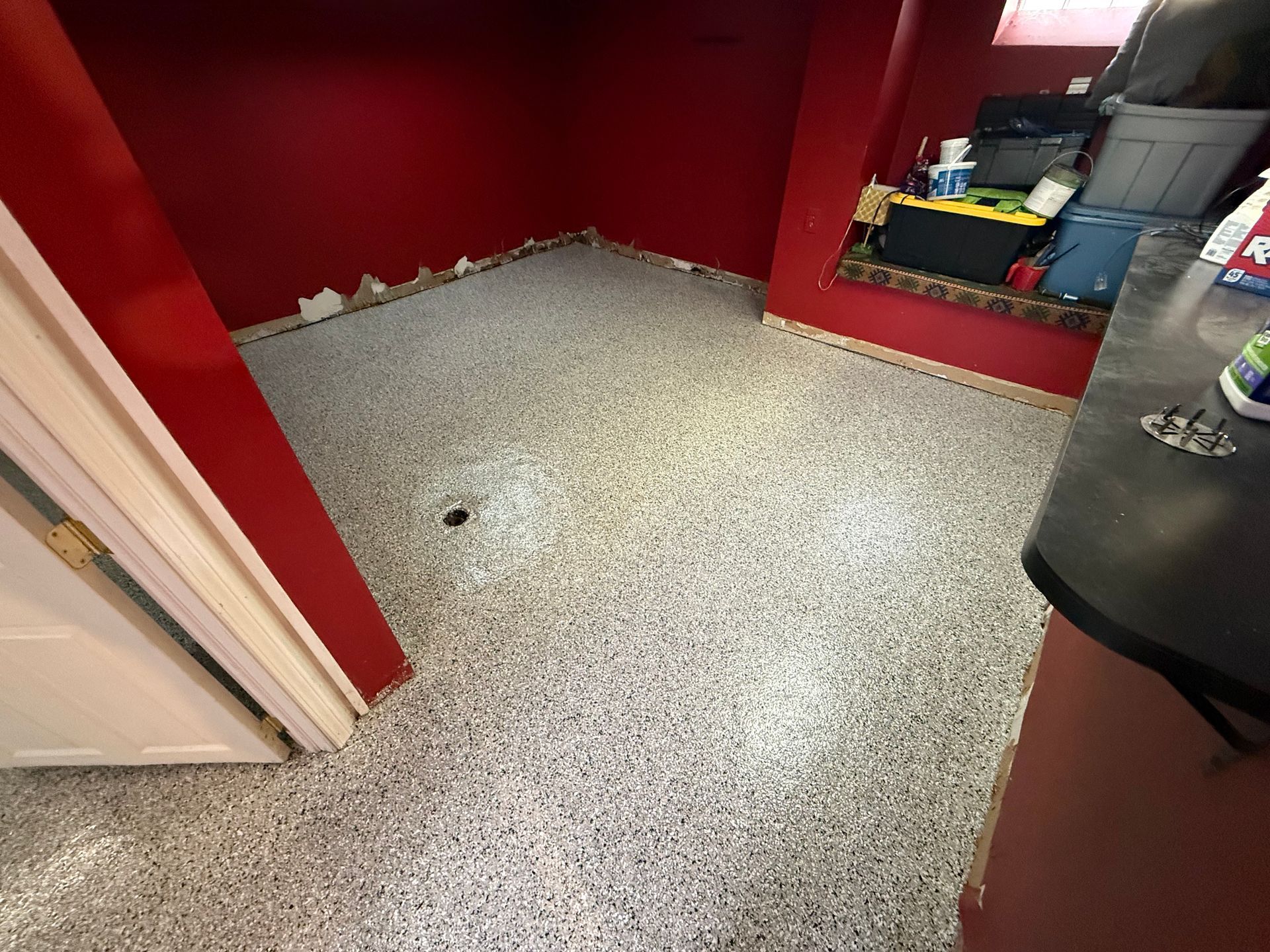 Red-walled small room with speckled gray floor and a built-in shelf on the right.