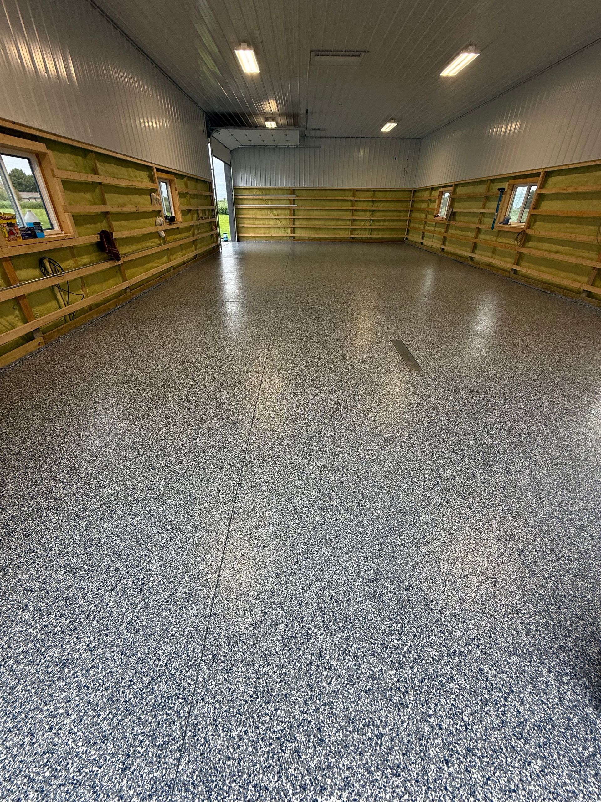 Indoor wooden-walled hall with a speckled gray floor and bright light at the far end