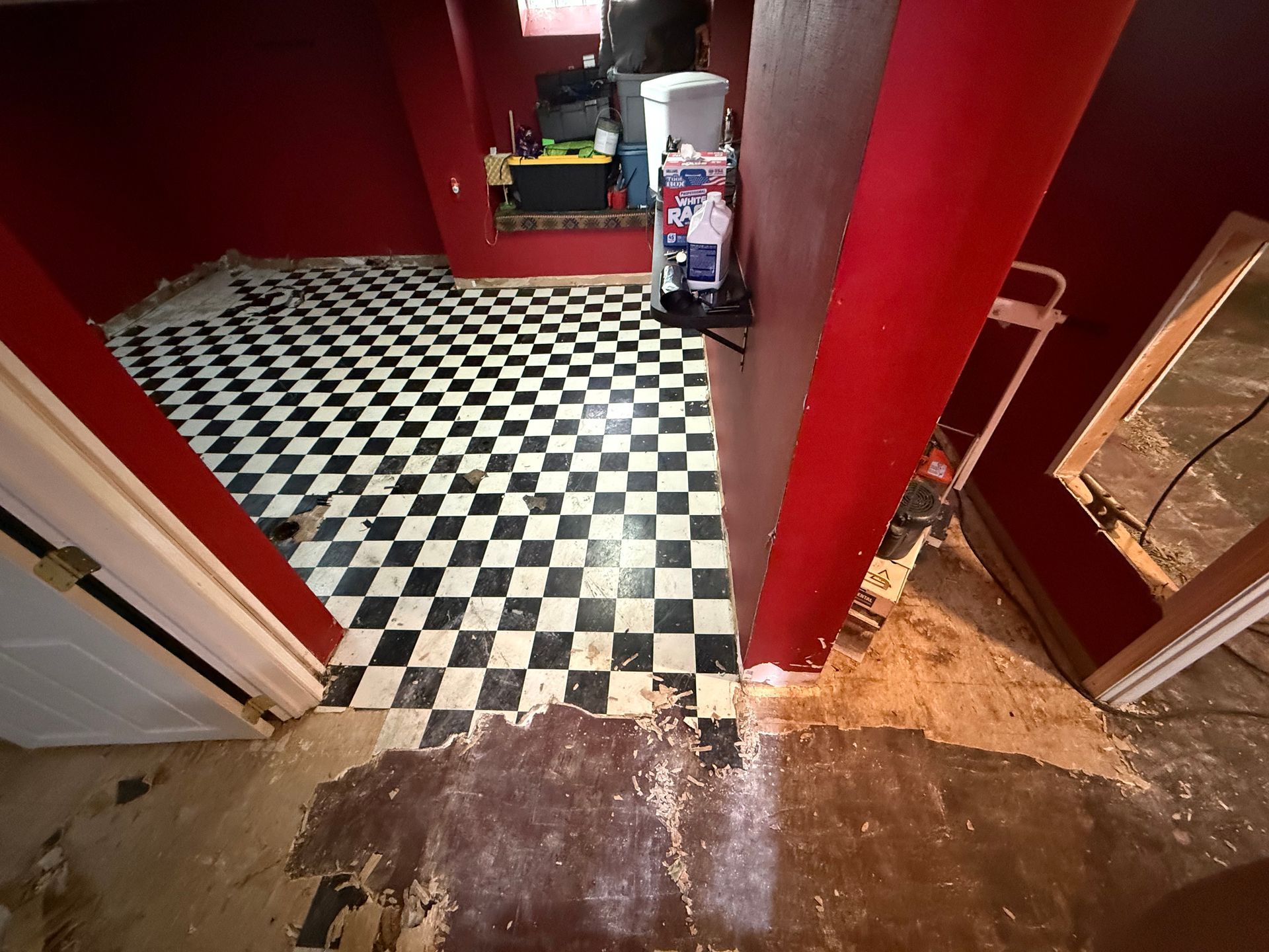 Red room with black-and-white checkered floor, doorway, and worn wooden threshold.